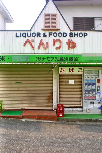 とんがり屋根に「LIQUOR & FOOD SHOP べんりや」の看板がある店