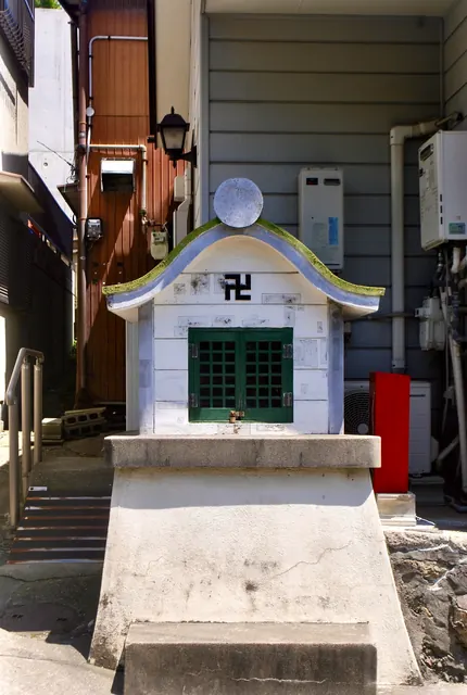 建物のあいだにたたずむ、白い小さなお堂