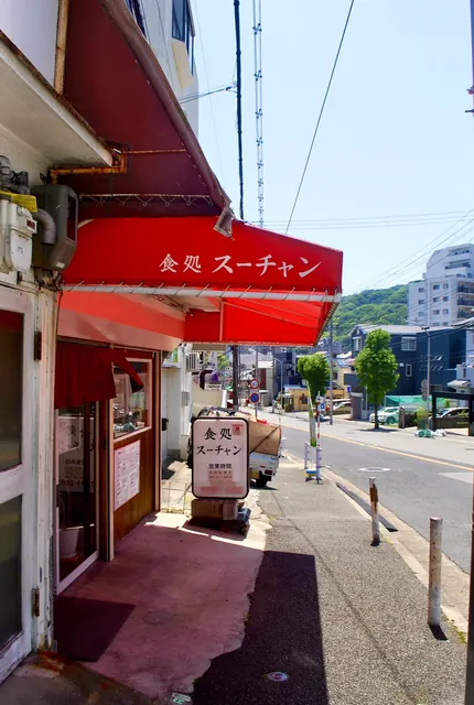 赤い日よけの食堂の前から、大通りと町並みを見渡す風景