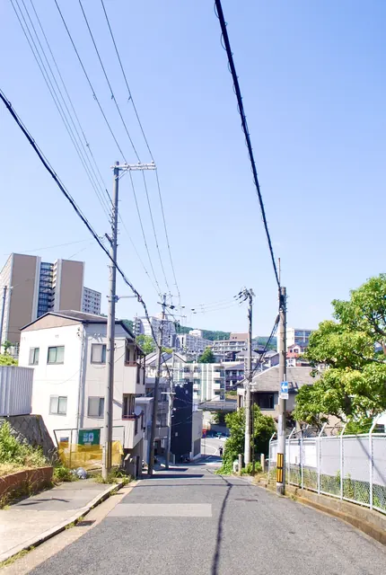 フェンスに沿って、遠くの町並みへ下っていく坂道