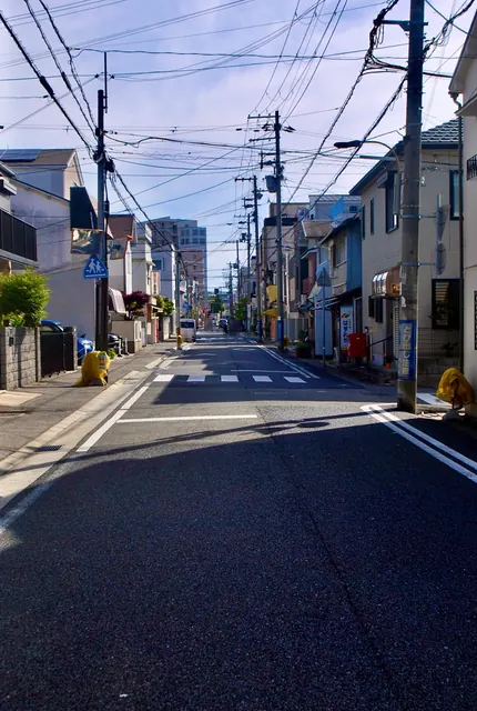 電線が空を横切って奥まで続く、人通りの少ない広い通り