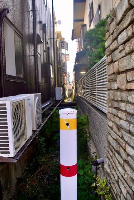 家と家のあいだの細い水路と、手前に立つ白いポール