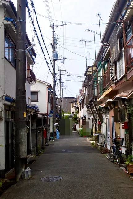 長屋と自転車、植木鉢が並ぶ、まっすぐな細い路地