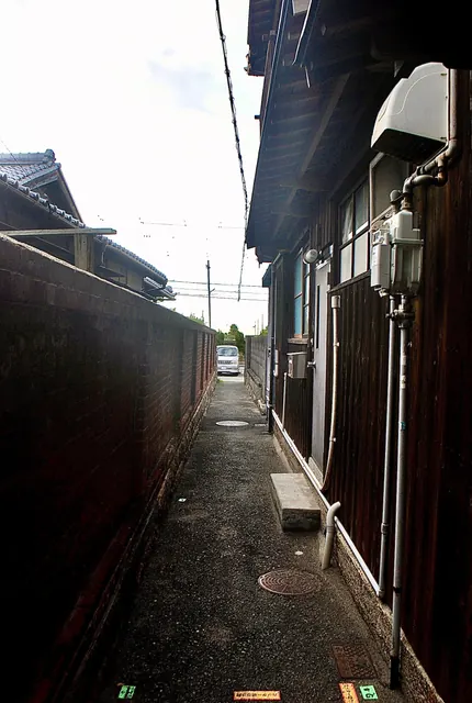 黒い板塀と古い家の壁に挟まれた、細い路地