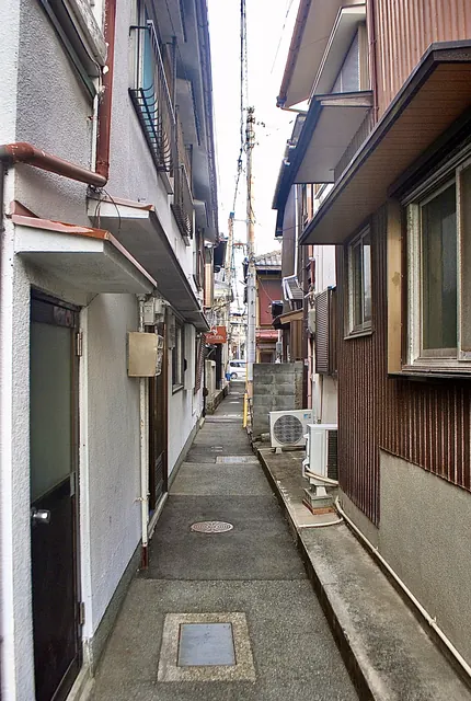 両側から家の軒が迫る、奥へ続く細い路地