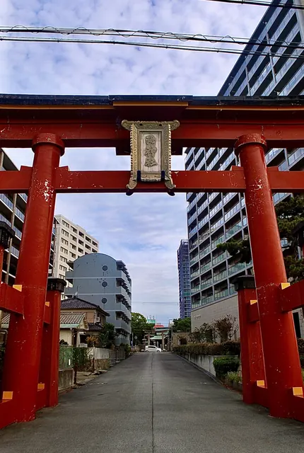 朱色の大きな鳥居をくぐり、まっすぐのびる道とマンション