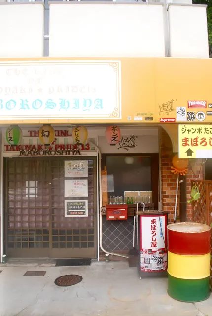 ちょうちんとドラム缶のある、にぎやかなたこ焼き屋の店先