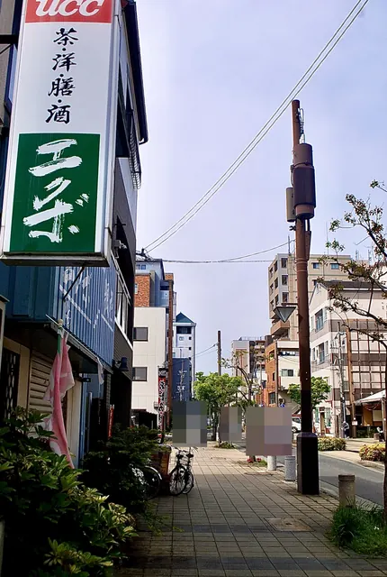 緑の「茶洋膳酒 エクボ」の看板と、並木の続く歩道