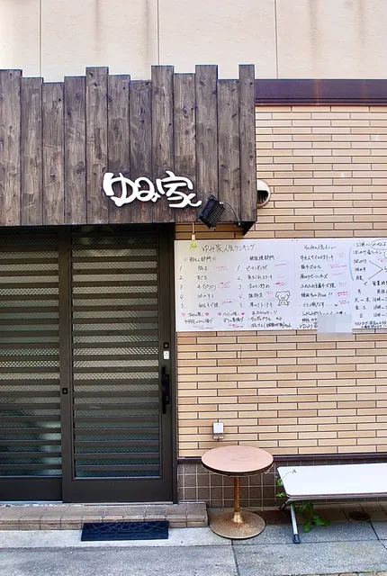 木の板の看板と、手書きのメニューボードが並ぶ店の入口