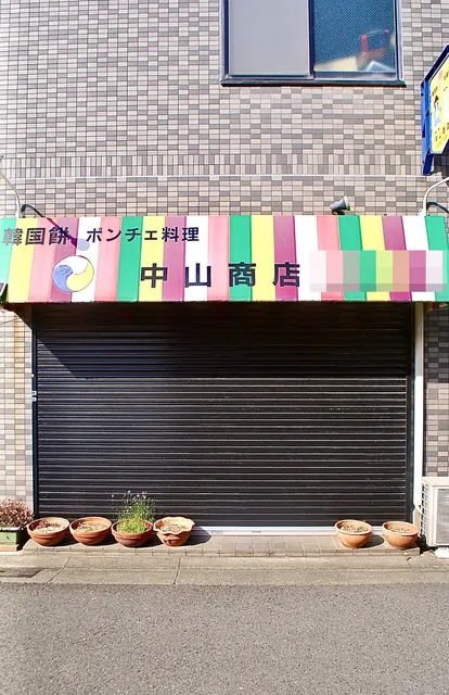 カラフルなしましまの日よけに「韓国餅・ポンチェ料理」と書かれた店