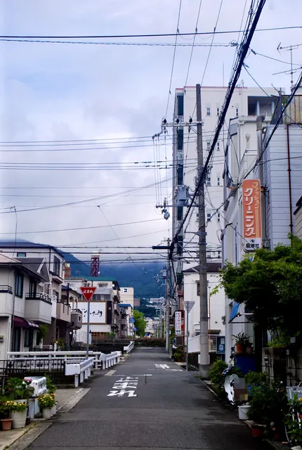 クリーニング店の看板の先に、六甲山の山並みが見える道