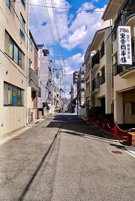 両側に建物が並び、奥まで続く明るい通りと、空に広がる雲
