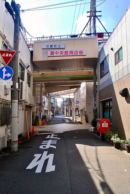 路面に「止まれ」と書かれた道の先に、商店街の入口が見える風景