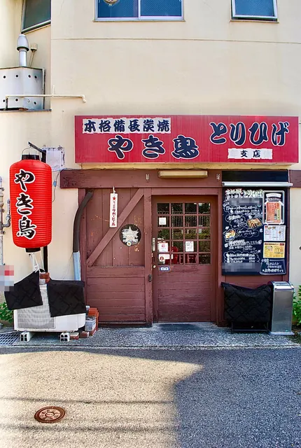 赤い提灯と古い木の扉、手書きの黒板が並ぶ店先