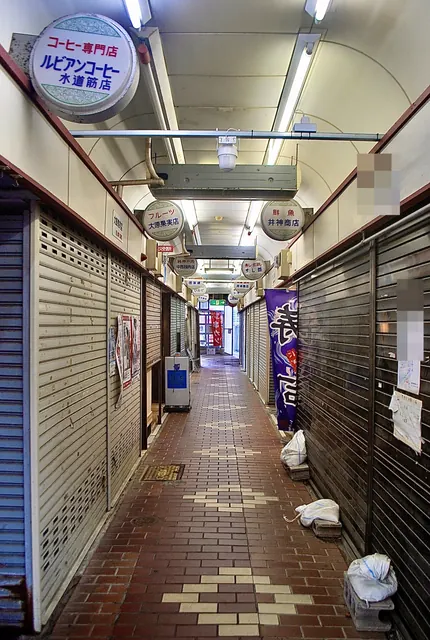 丸い看板が天井から下がり、シャッターの並ぶ市場の通路