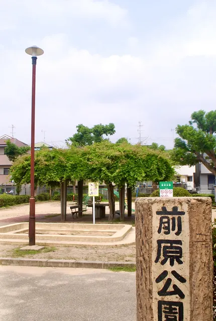 「前原公園」と書かれた石の柱と、藤棚のある広場