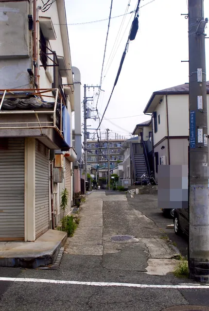 シャッターの閉まった古い家の脇を、上へ続く細い坂道