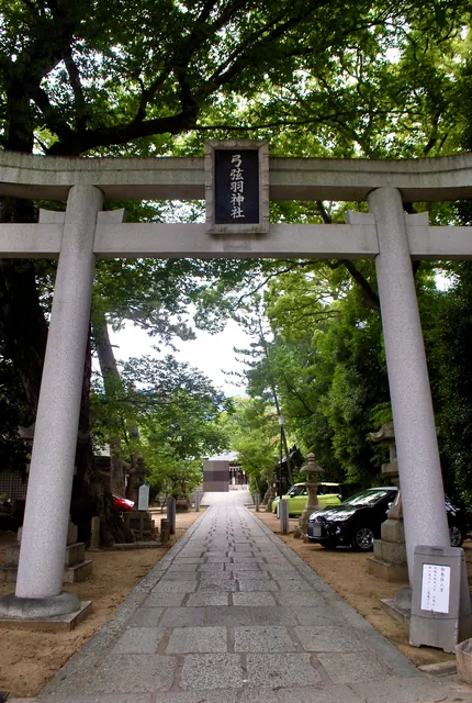 石の鳥居の奥に、木々に囲まれた参道と拝殿が見える風景
