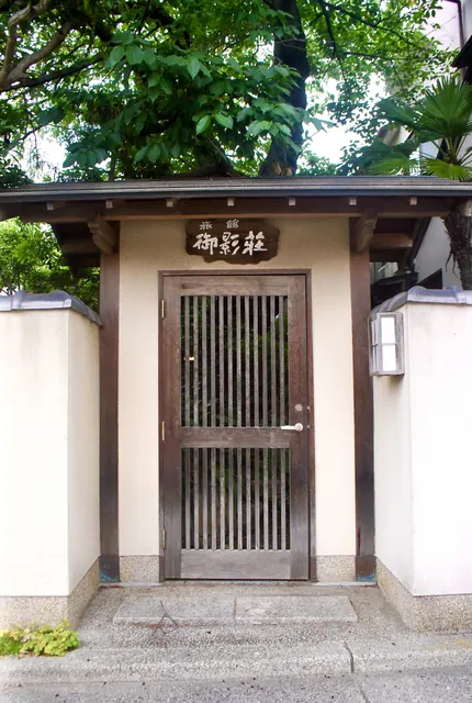 瓦屋根の門に木の格子戸がはまった、料理旅館の入口