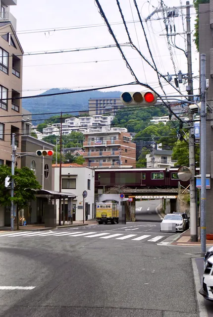 山並みとマンションを背に、阪急電車が鉄橋を渡る交差点