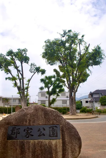 「郡家公園」と刻まれた石と、大きな木の立つ広場