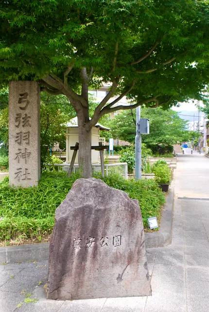 「弓弦羽神社」と刻まれた石柱と、公園の石碑が並ぶ入口
