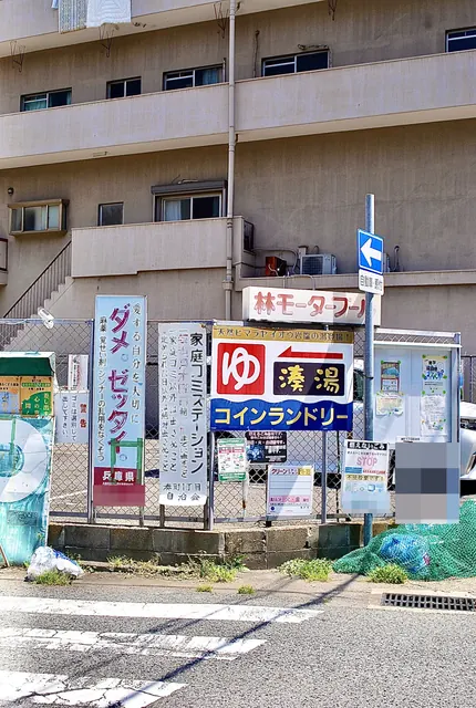「湊湯」の大きな看板と、ごみ出しのお知らせが並ぶフェンス