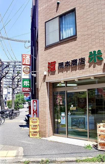 「酒」「米」「たばこ」の看板と、ビールケースが並ぶ店先