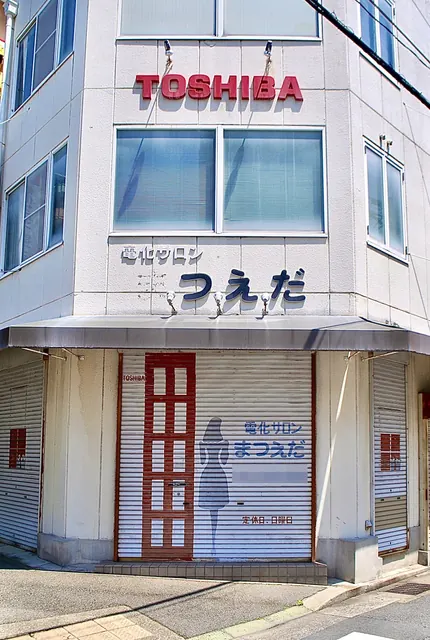 人の絵が描かれたシャッターと、東芝の看板がある電器店