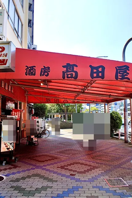 赤い大きなテントの「酒房 高田屋」の下を行き交う通り