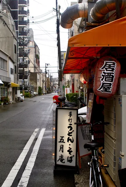 「居酒屋」と書かれた大きな赤提灯と、手打ちうどんの看板