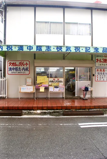 「タオルのデパート」の看板と、タオルが並ぶ店先