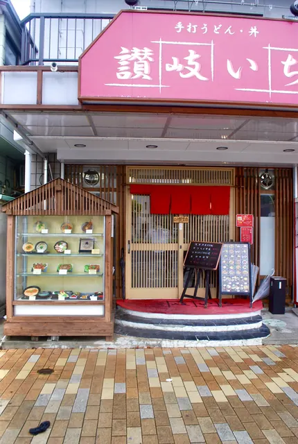 木の屋根のショーケースに食品サンプルが並ぶ、食堂の店先