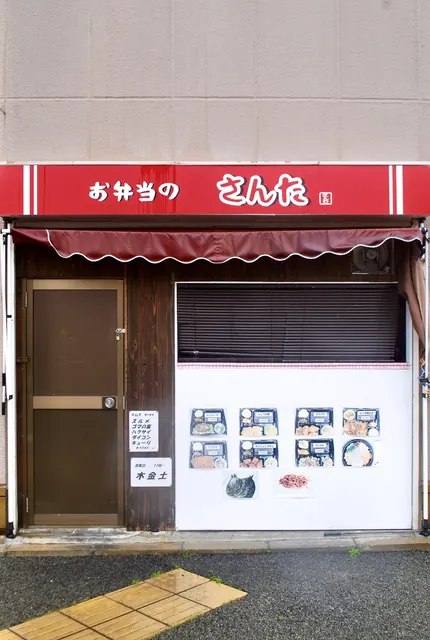 弁当の写真が並ぶ白い壁と、えんじ色の日よけ