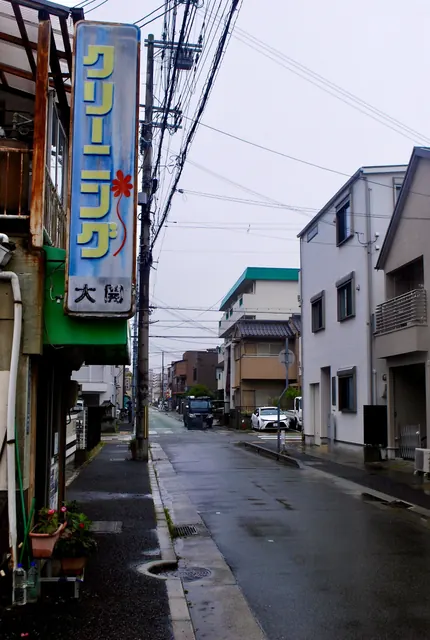 大きなクリーニングの看板の下から、雨の通りを見る風景