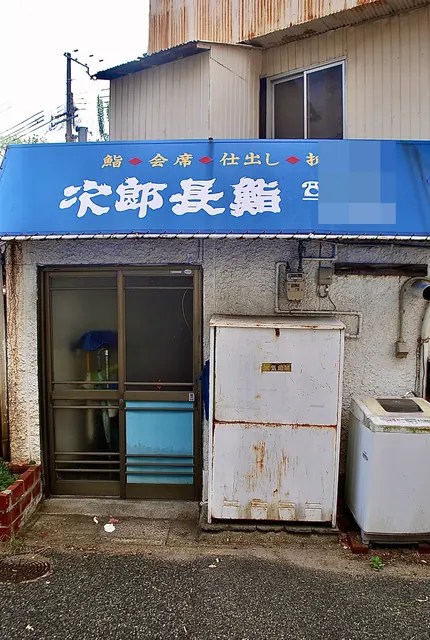 青い日よけに「次郎長鮨」と書かれた店の、裏口の風景