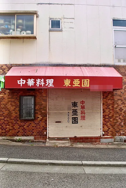 赤い日よけに「中華料理 東亜園」の文字がある、レンガ張りの店