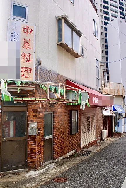「中華料理」の縦看板と、旗の飾りがさがるレンガ張りの店