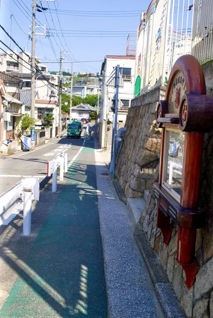 石垣に掛かる木彫りの看板の脇を、上っていく坂道
