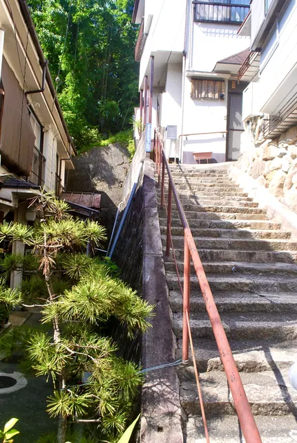 松の木の脇を、赤い手すりに沿って上る石段