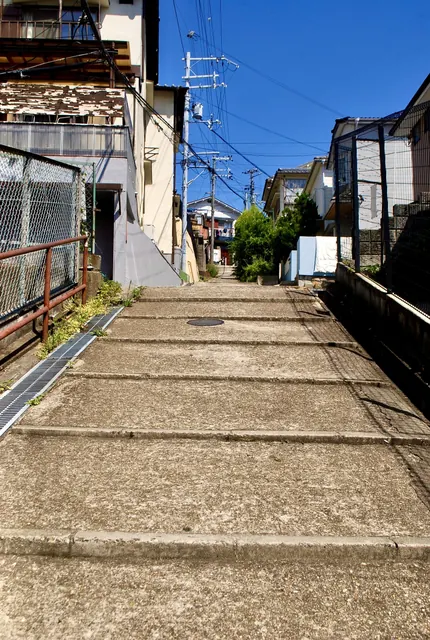 フェンスに沿って、奥へまっすぐ上る広い坂道