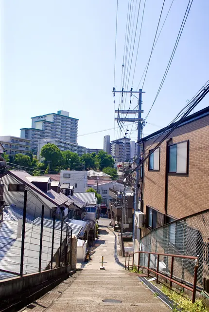 家々の屋根の向こうに、大きな団地がそびえる風景