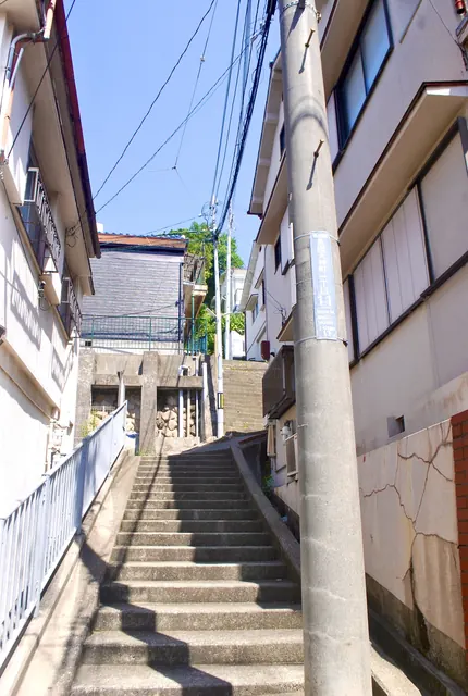 建物に挟まれ、白い手すりに沿って上る石段