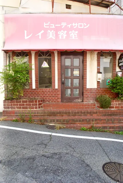 ピンクの日よけとレンガの壁の、昔ながらの美容室