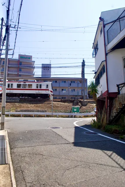 交差点の先の線路を、神戸電鉄の電車が走る風景