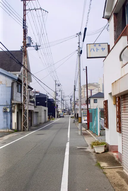 「喫茶 ハトヤ」の看板の先に、電柱がずらりと続くまっすぐな道