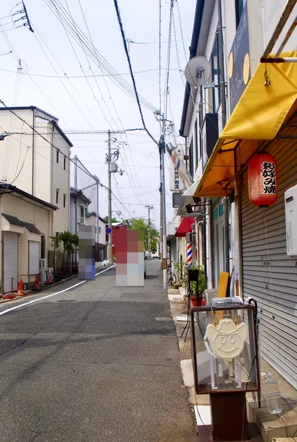 「お好み焼」の赤い提灯とサインポールが並ぶ、まっすぐな通り
