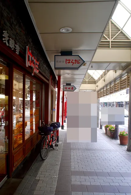 パンの並ぶ大きな窓と自転車、矢印形の看板が続く商店街