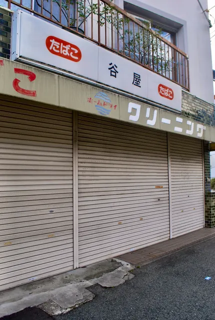 「たばこ」「クリーニング」の色あせた看板と、下りたシャッターを近くから見た店先
