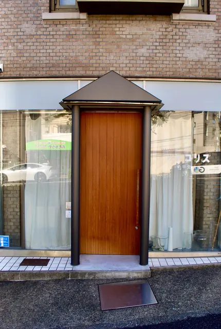 レンガの建物の一階にある、とんがり屋根のついた木の扉